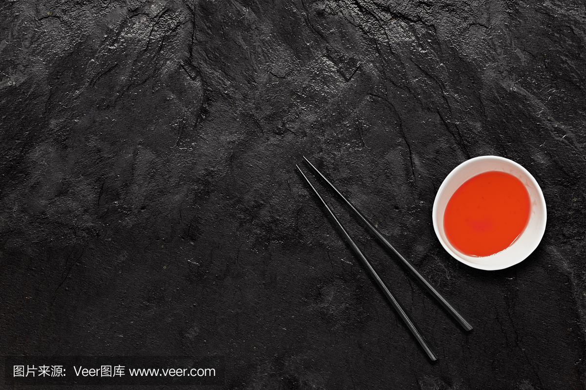 筷子和糖醋汁碗在黑石板上。