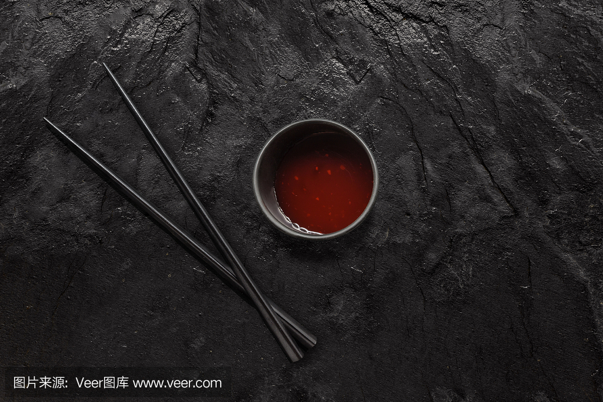 木筷子和糖醋酱碗上的黑石板。